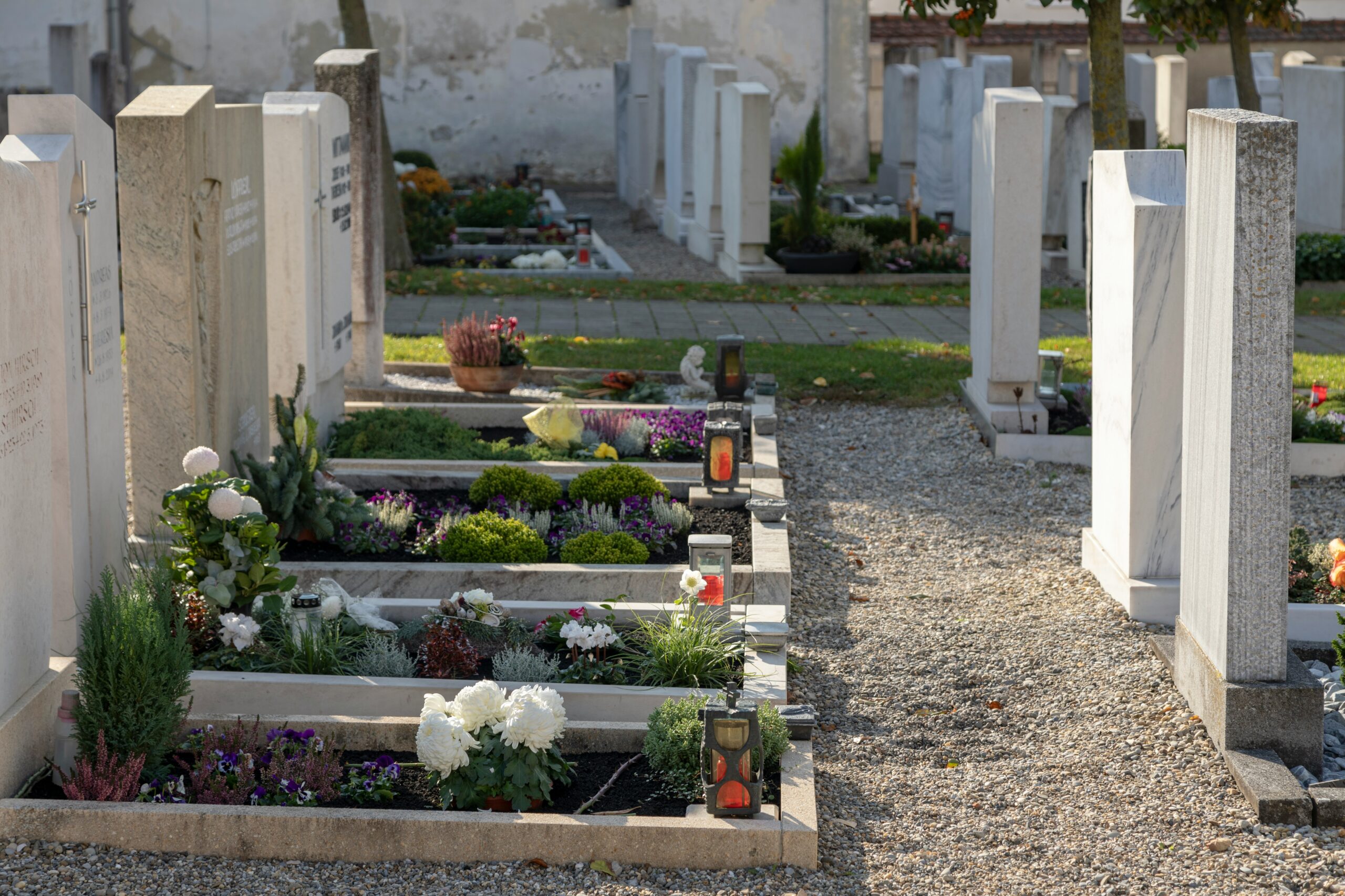 Mehrere Gräber, die mit Blumen geschmückt sind, nebeneinander